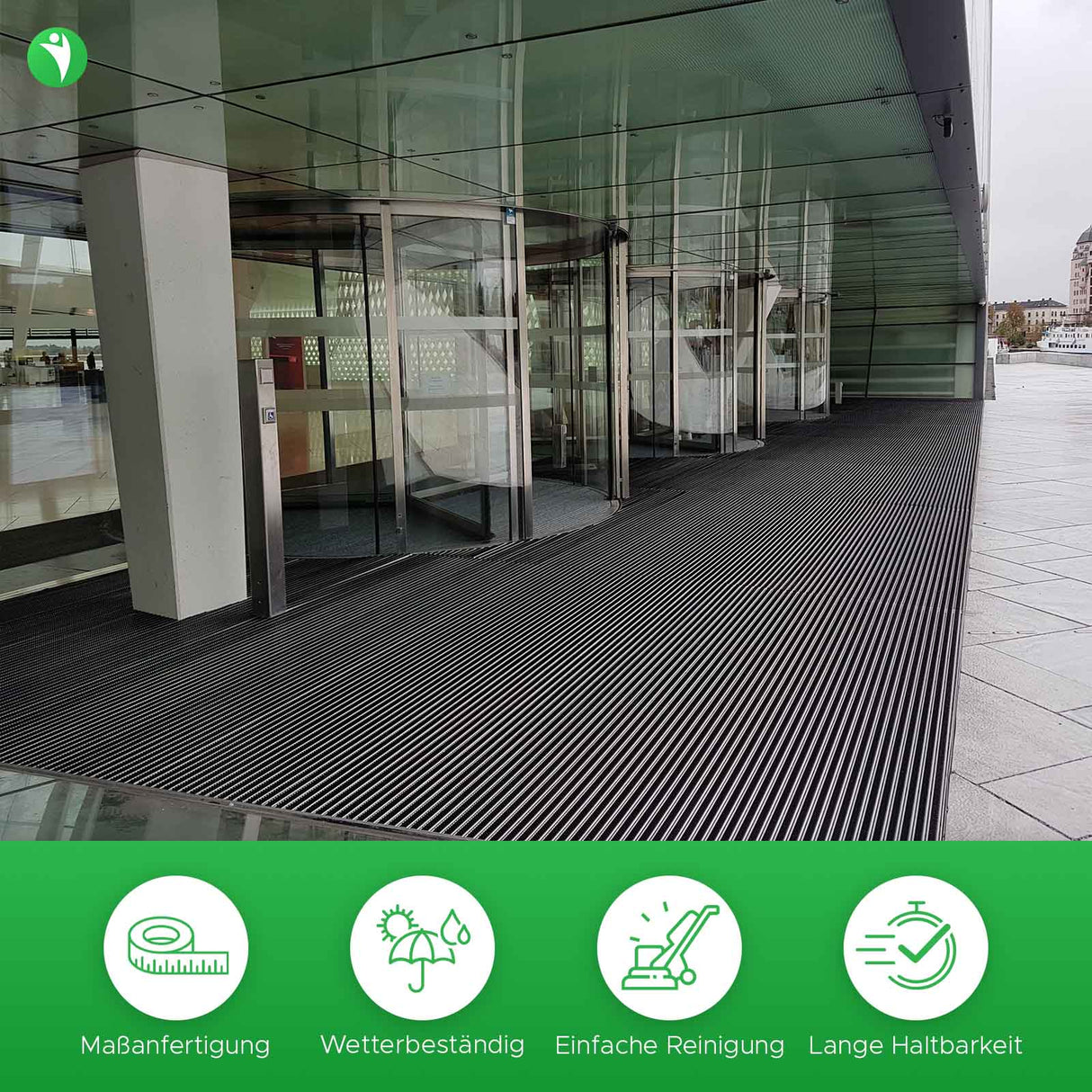 Alupro Bürste in Anwendung. Verlegte Aluprofilmatte vor großem Gebäude mit Drehtüren